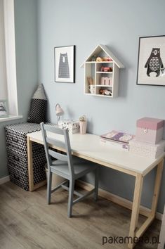 a child's room with blue walls and wooden flooring, including a white desk