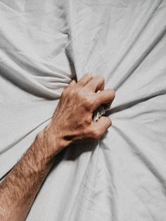 a man's hand on top of a white sheet covering his face and arm