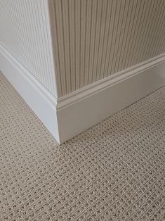 the corner of an empty room with carpeting on the floor and in between two walls