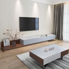 a living room with white furniture and a flat screen tv mounted on the wall above it