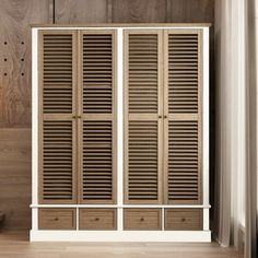 a white cabinet with wooden shutters and drawers in front of a wood paneled wall