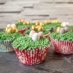 cupcakes with green frosting and decorated eggs on top are sitting on a table