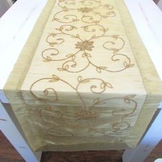 an embroidered table runner on top of a wooden table