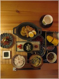 an overhead view of various food items on a bamboo mat with chopsticks and forks