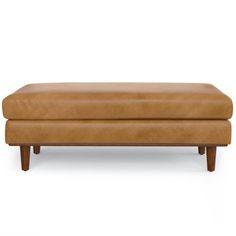 a tan leather ottoman with wooden legs