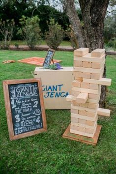 wooden blocks stacked on top of each other in front of a chalkboard sign and tree