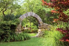 a stone arch in the middle of a garden