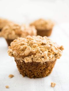 two muffins with crumbs sitting on top of a white table cloth