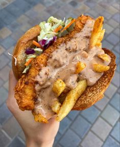 a person is holding up a chicken sandwich with fries and coleslaw on it