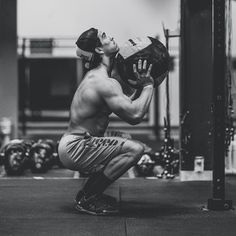 a man squatting down while holding a medicine ball