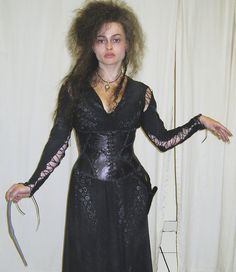 a woman dressed in black holding a knife and wearing a dress with laces on it