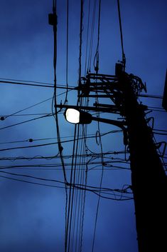 an overhead view of power lines and telephone poles at dusk with the moon in the distance