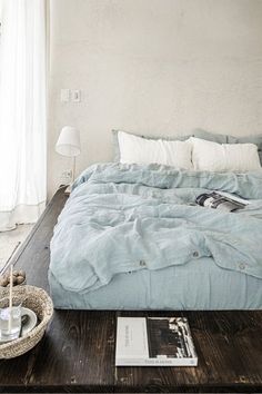 a bed sitting on top of a wooden floor next to a white lamp and window