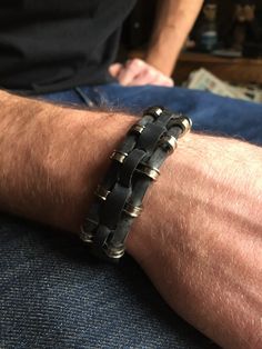 a man's arm wearing a black leather bracelet