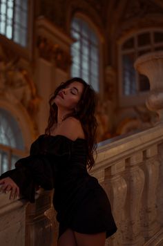 a woman leaning on a railing in a black dress