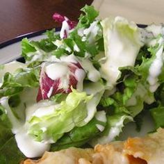 a salad and pita sandwich on a plate with dressing drizzled over the lettuce