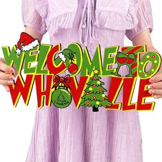 a woman in a pink dress holding up a welcome whizzle sign with christmas decorations on it