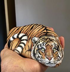 a hand holding a painted tiger figurine in it's palm