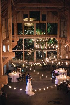 a bride and groom standing in the middle of a barn