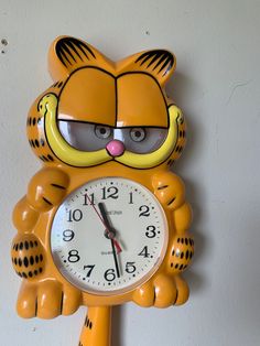 a yellow tiger clock with glasses on it's face hanging from the side of a wall