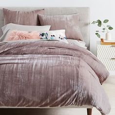 the bed is made up with pink and grey comforters