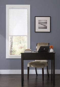 a laptop computer sitting on top of a wooden desk in front of a white window