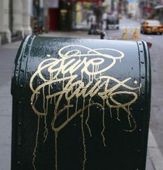 a black mailbox with gold graffiti on it