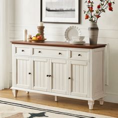 a white buffet table with fruit and flowers on it in front of a framed photograph