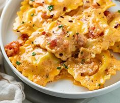 a white plate topped with ravioli covered in cheese and meat sauce next to a fork