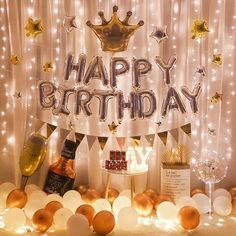 a happy birthday banner with balloons and confetti in front of white curtained backdrop