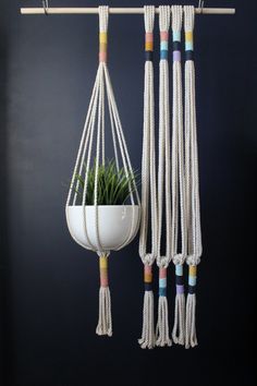 macrame plant hangers with rope and potted plants in them on a black wall