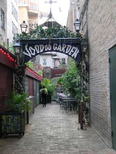 an alley way with tables and chairs under a sign that says sudda garden on it