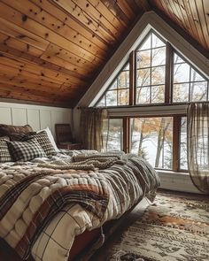 a large bed sitting under a window in a bedroom next to a rug on the floor