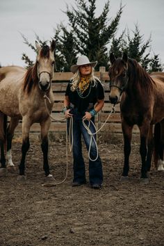 a woman standing next to two brown horses