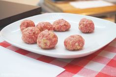 a white plate topped with meatballs on top of a red and white checkered table cloth