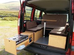 the back end of a red van with its doors open and seats folded down on it