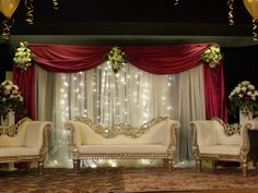 the stage is decorated with white couches and red drapes, along with flowers