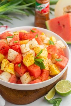 a white bowl filled with watermelon, pineapple and minty garnish