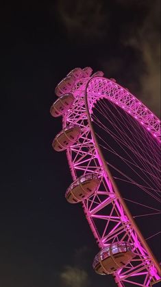 the pink ferris wheel is lit up at night