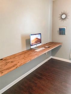 a computer monitor sitting on top of a wooden shelf next to a window in a room