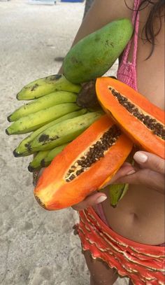 a woman holding two pieces of fruit in her hand and some bananas on the other side