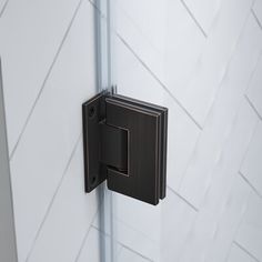 a black door handle on the side of a white wall with chevroned tiles