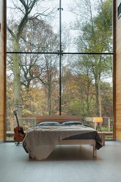 a bed sitting in the middle of a bedroom next to a window with trees outside