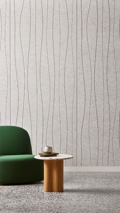 a green chair sitting next to a white table on top of a cement floor in front of a wall