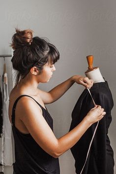 a woman is working on a black dress in her studio by herself for the camera