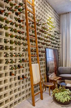 a living room filled with furniture and lots of wine bottles on the wall next to a ladder