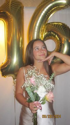 a woman in a white dress holding a bouquet of flowers next to the number 20 balloon