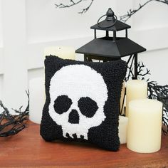 a black and white skull pillow sitting on top of a wooden table next to candles