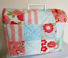 a pink and blue patchwork purse sitting on top of a white table next to a wall