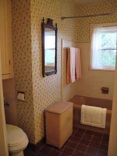 a bath room with a toilet a sink and a mirror on the wall next to a window